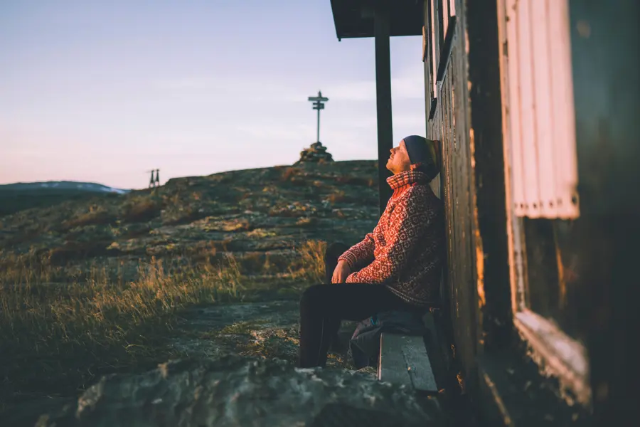 Mann lener seg mot hyttevegg