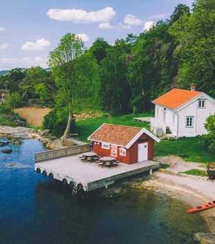 Hvit hytte med rødt anneks, ved hvit sandstrand